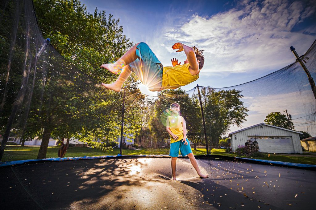 Brothers jumping on the trampoline in backyard